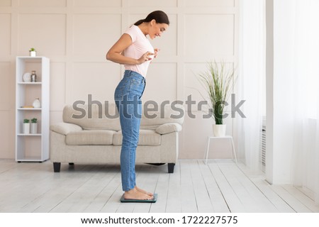 Weight Loss Concept. Girl Standing On Weight-Scales Weighing Herself Crossing Fingers Slimming At Home. Copy Space Photo stock © 