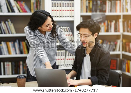 Young mexican professor assisting male asian student in glasses, helping him with studies in college library Foto d'archivio © 
