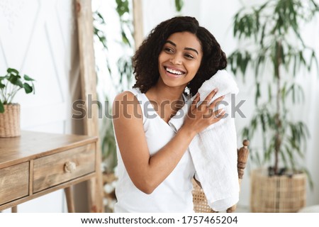Home Haircare Concept. Smiling African Woman Drying Wet Hair With Towel After Shower, Standing In Cozy Bathroom, Free Space