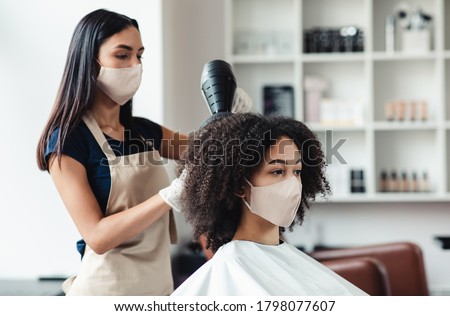 Be safe and beautiful. Hairdresser and customer wearing protective masks at beauty salon, close up