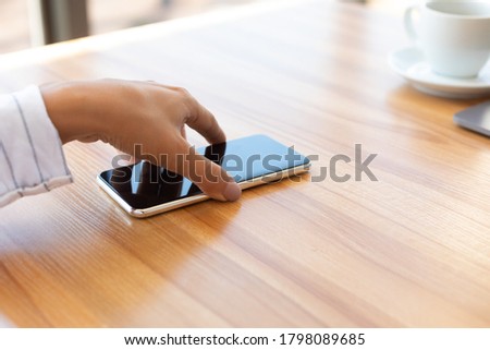 Notification. Closeup of lady taking cell phone off desktop or laying it down on table Foto stock © 