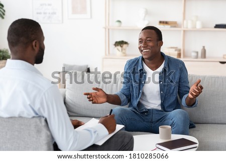 Successful Therapy. Cheerful black man talking to psychologist on meeting at his office, sharing his progress with doctor