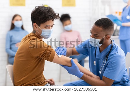 Covid-19 Vaccination. Asian Man Receiving Coronavirus Vaccine Intramuscular Injection In Arm During Doctor's Appointment In Hospital. Corona Virus Immunization, Protection, Medicine Treatment Concept