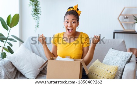 Yes. Emotional black female buyer customer received long-awaited package, screaming with joy, opening cardboard box at home, satisfied with great purchase. Reliable postal courier service concept
