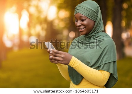 Similar – Image, Stock Photo Positive Muslim woman using smartphone on embankment
