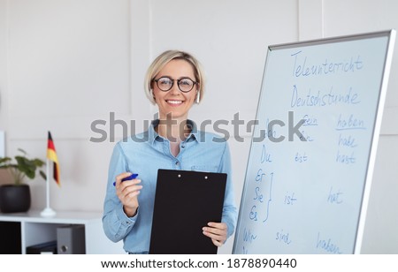 Online schooling concept. Portrait of positive German teacher posing near blackboard with grammar rules, looking at camera and smiling, indoors. Foreign languages tutor giving remote lesson ストックフォト © 