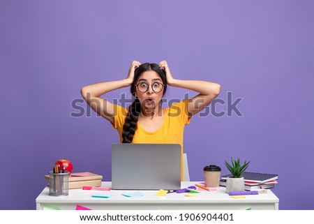 Deadline Concept. Portrait of shocked surprised indian woman sitting at desk with laptop computer and grabbing her head isolated over purple studio background wall. Stressed lady at workplace Stock foto © 