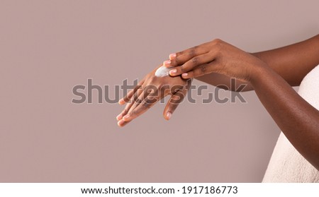 Dry Skin Treatment. Unrecognizable African American Woman Applying Moisturizing Cream On Hands, Black Female Rubbing Nourishing Body Lotion To Palm Over Grey Background, Cropped Image, Panorama Stock foto © 