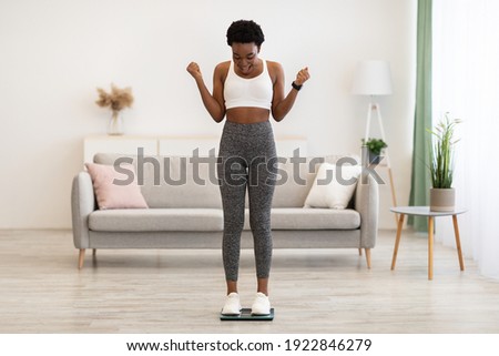 Great Weight Loss. Excited African American Woman On Weight-Scales Shaking Fists In Joy Weighing After Successful Slimming At Home. Weight-Loss Success Concept. Full Length Photo stock © 