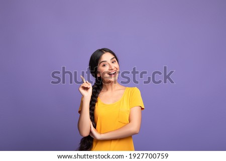 I Have An Idea. Portrait of cheerful young indian woman having great thought, finding inspiration or solution to problem. Positive lady pointing finger up isolated over purple studio wall, copy space