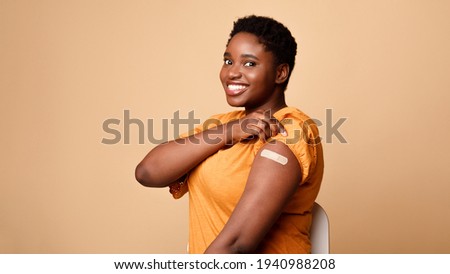Black Woman Showing Vaccinated Arm After Vaccine Injection, Beige Background