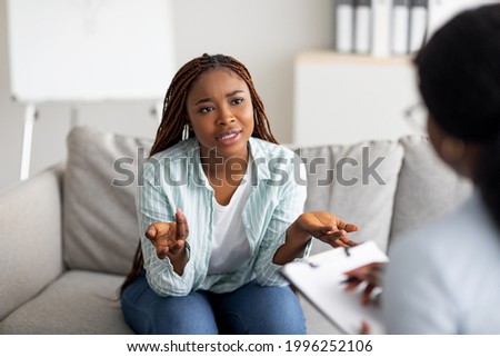 Mental health and psychological assistance concept. Young worried black woman having counseling session with psychotherapist at clinic. PTSD disorder, anxiety treatment Stock foto © 