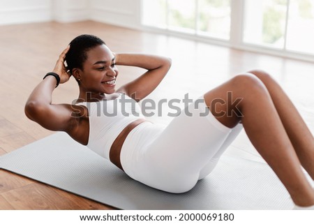 Home Training. Sporty Smiling African American Woman Exercising Doing Sit-Ups Abs Crunches Exercise Indoors Lying On Yoga Mat. Sport Workout Routine, Morning Physical Training Exercises Concept Сток-фото © 