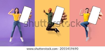 Glad excited young asian, european women and black guy jumping from joy and show phone with empty screen, isolated on colored background, collage. Great advice, offer and digital ad, new app, panorama 商業照片 © 