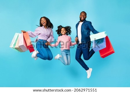 Shopping Together. Happy Family Of Three Excited African American People Jumping Up High In The Air, Holding Hands Carrying Many Bright Shopper Bags Isolated Over Turquoise Studio Background, Advert Сток-фото © 