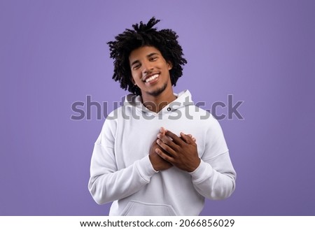 Kind African American teenager placing hands on his heart, expressing love and affection on violet studio background. Friendly black teen guy showing romantic feelings or kindness Foto d'archivio © 