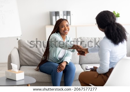 Effective therapy. Cheerful female patient and psychologist shaking hands at office. African American woman feeling grateful to her psychotherapist after successful treatment Stockfoto © 