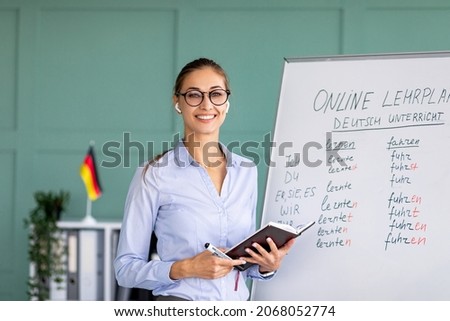 Portrait of cheerful German teacher standing near blackboard, conducting internet lesson and smiling at camera. Positive tutor giving language class on video call or web conference Stockfoto © 