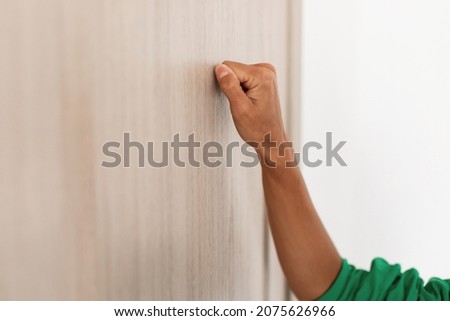 Closeup view of young unrecognizable woman knocking on the wooden door, female visitor standing in entrance, guest lady wants to come in, free copy space, selective focus on fist hand Сток-фото © 