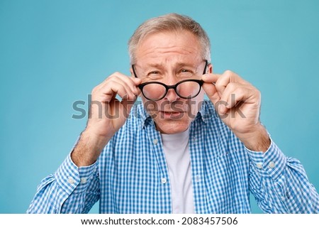 Poor Eyesight. Senior Man Can't See, Squinting Eyes Wearing Glasses Having Problems With Vision, Looking At Camera At Blue Studio. Ophtalmic Issue, Bad Sight In Older Age, Macular Degeneration Concept Сток-фото © 