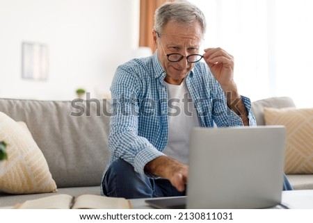 Poor Eyesight. Senior Man Squinting Eyes Using Laptop Wearing Eyeglasses Having Problems With Vision Sitting On Couch. Ophtalmic Issue, Bad Sight In Older Age, Macular Degeneration Concept Stok fotoğraf © 