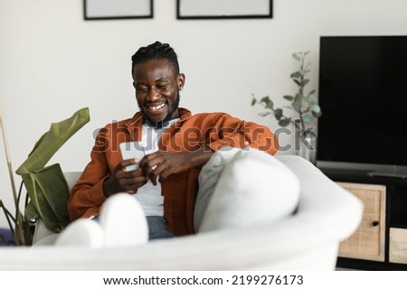 Similar – Image, Stock Photo Young black man holding wireless headphones while wearing a white sweatshirt, against a blue wall looking away with confidence. Selective focus