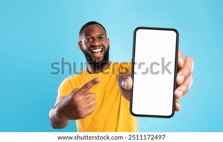 Image, Stock Photo Young black man holding wireless headphones while wearing a white sweatshirt, against a blue wall looking away with confidence. Selective focus