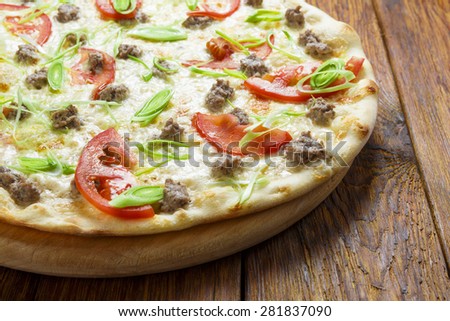 Delicious seafood pizza with tuna fish, tomatoes and leek - thin pastry crust at wooden table background