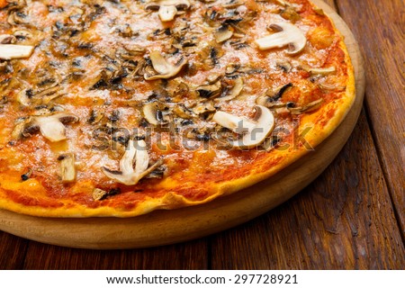 Delicious pizza with mushrooms - thin pastry crust isolated at wooden background on wooden desk