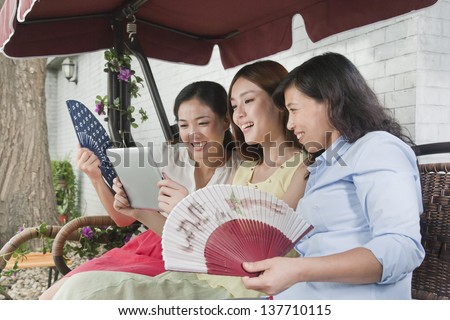 Three Women with Fans and Tablet Outdoors
