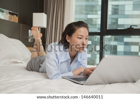 Businesswoman working on her laptop in the bed