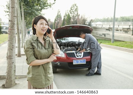 Woman Talking on Phone While Mechanic Fixes Her Car