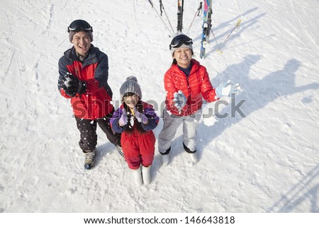 Smiling Family Throwing Snow Up in the Air in Ski Resort