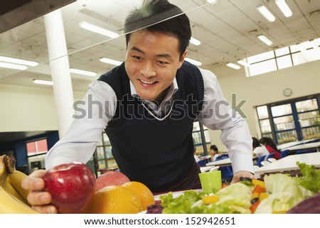 Teacher reaching for healthy food in school cafeteria