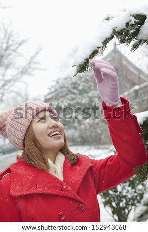 Young woman reaching for a branch in the snow