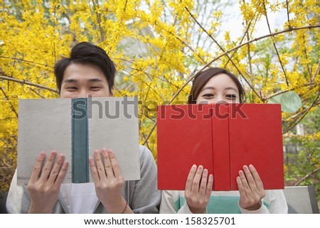 Young happy couple sitting side by side and reading their books