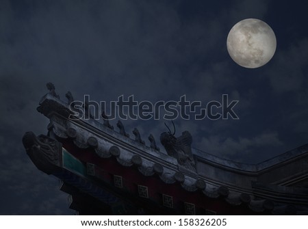 Close-up of ornate roof tiles on Chinese building with moon background