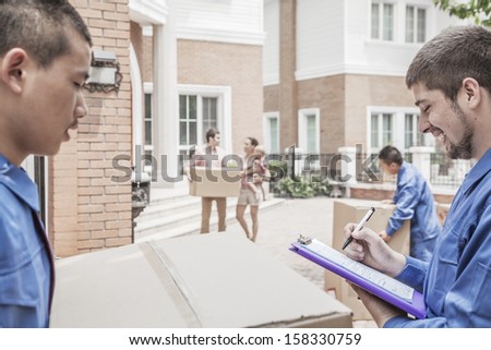 Mover holding clipboard and invoice with family in the background
