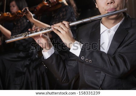 Flautist holding and playing the flute during a performance