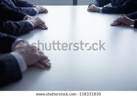 Close-up on folded hands of business people at the table