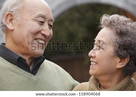 Portrait of laughing senior couple in front of round arch