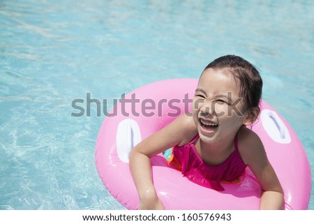Portrait of cute little girl swimming in pool with pink tube