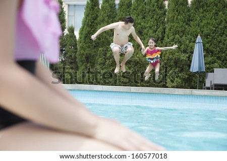 Father and daughter holding hands and jumping into pool