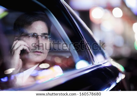 Businessman on the phone and looking out car window at night