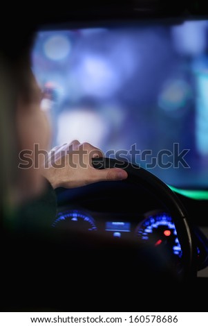 Over the shoulder view of businessman driving at night in city