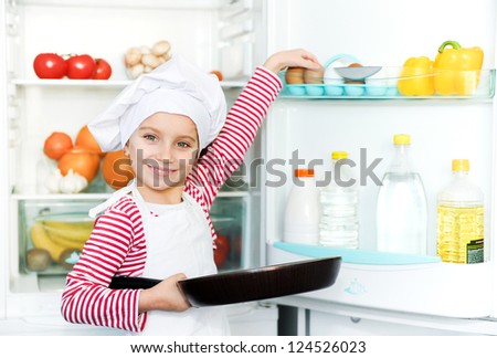little girl gets eggs out of the refrigerator