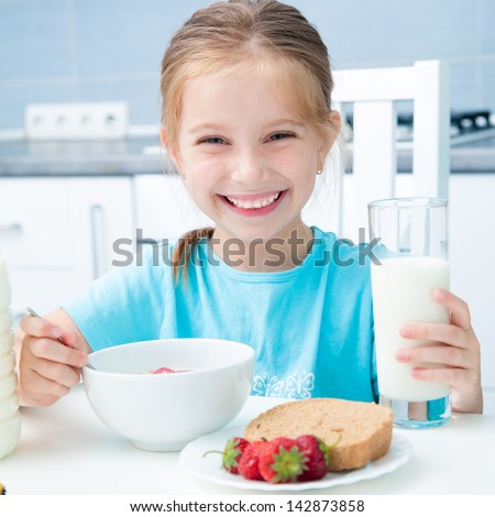 cute smiling little girl drinking milk in the kitchen