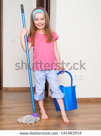 happy little girl washing the floor with a mop at home