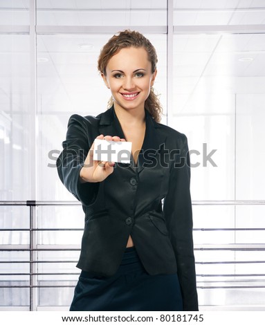 businesswoman in black suit holding blank empty sign. office background