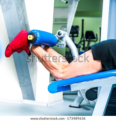 pretty athletically built sportsman doing leg exercises at the gym